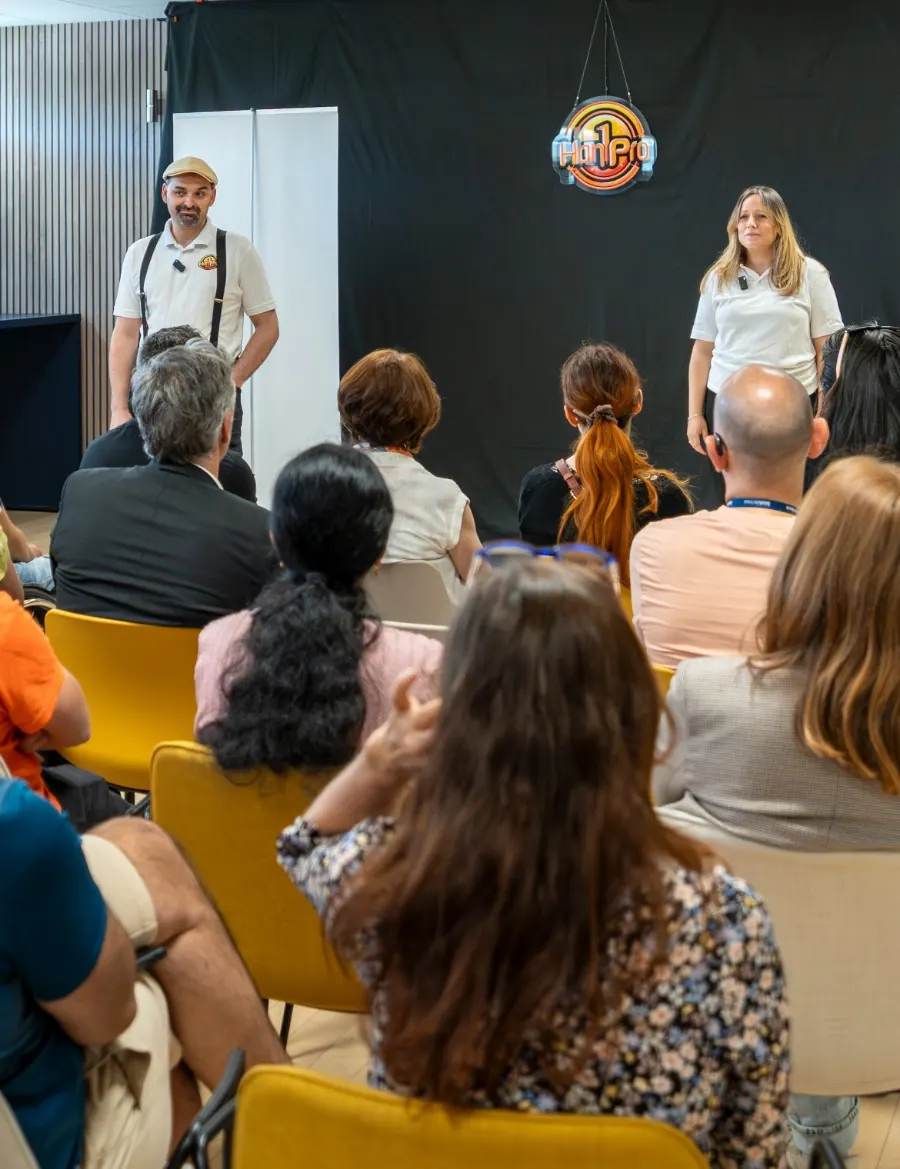 Comedy Club Han1Pro : deux comédiens sur scène sous le néon Han1Pro devant une salle de salariés, lors d'une animation de sensibilisation aux handicaps en entreprise